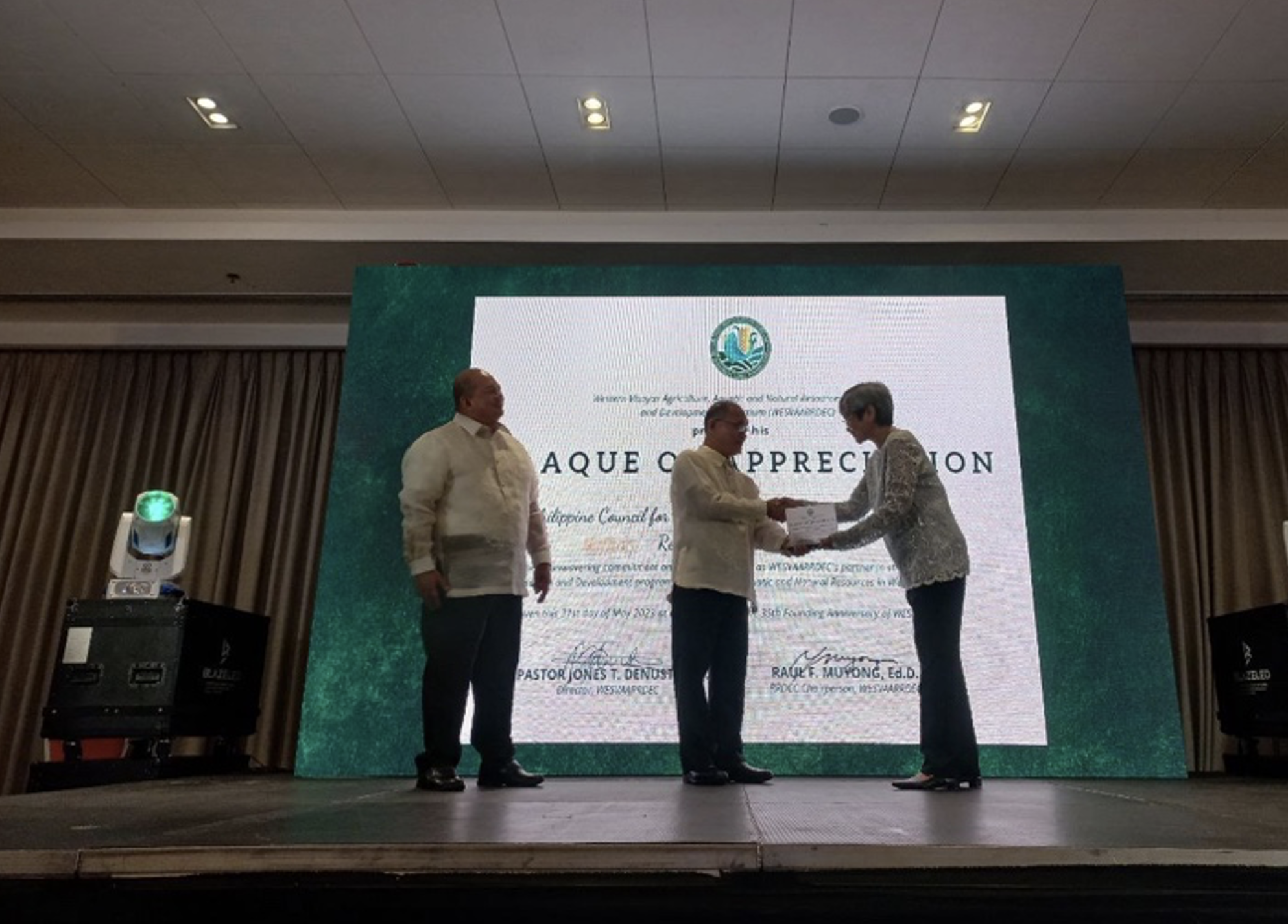 Dr. Pastor Jones T. Denusta and Dr. Raul F. Muyong giving the plaque of appreciation for DOST-PCAARRD to Dr. Mari-Ann M. Acedera. (from left to right)